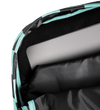 Close-up of a laptop compartment inside a backpack, showing a gray laptop resting on black padded lining with a black and mint green patterned exterior visible along the edge.