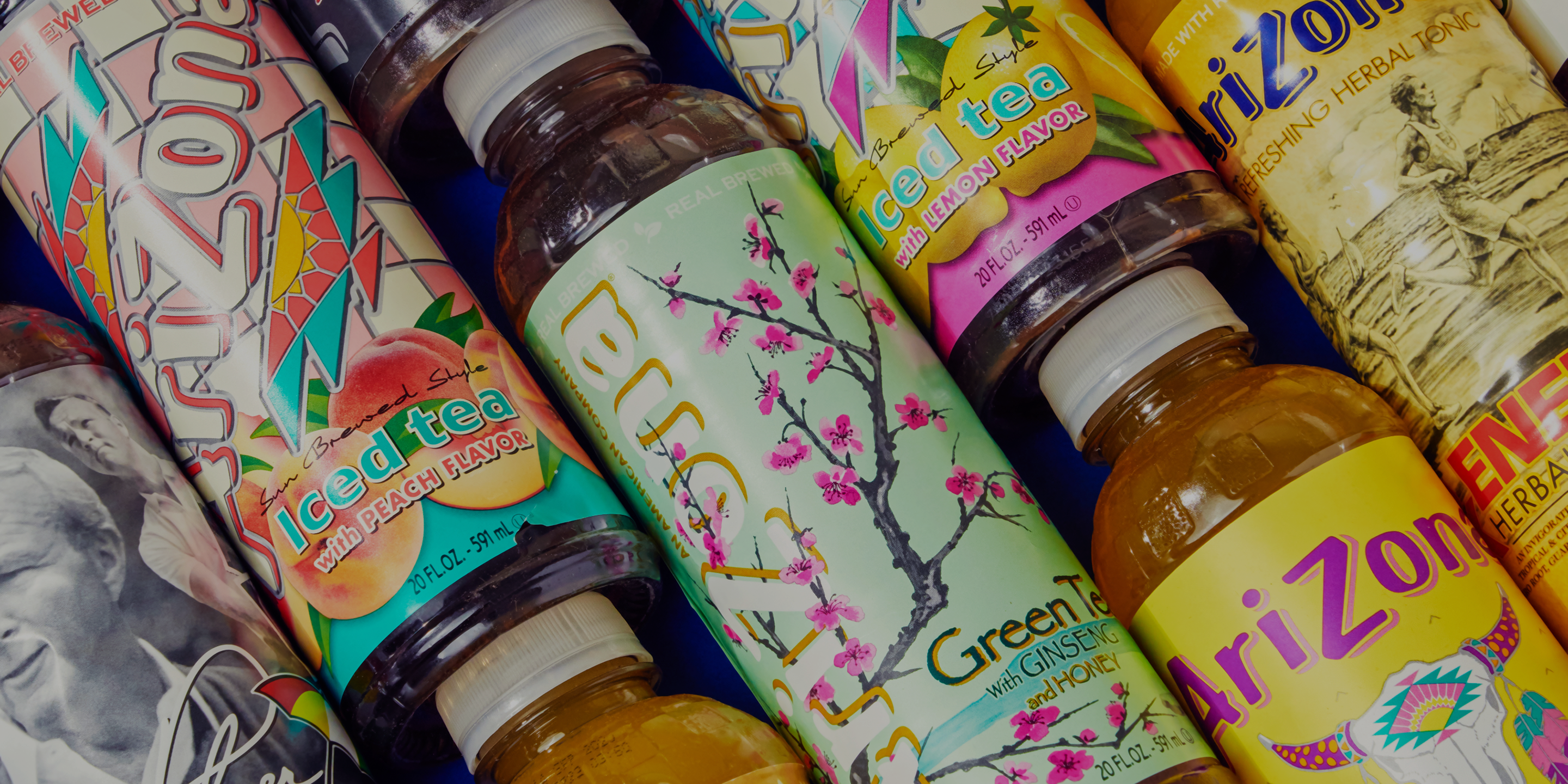 Collection of Arizona iced tea bottles with colorful labels on a blue background.
