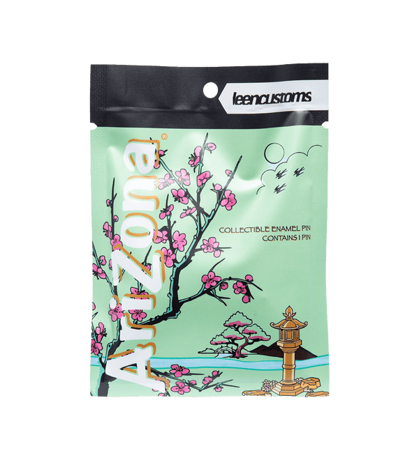 A collectible enamel pin in a clear resealable pouch by leencustoms, featuring a mint green background with cherry blossom illustrations, the word 'Arizona' in large gold letters, and a small lantern at the bottom.