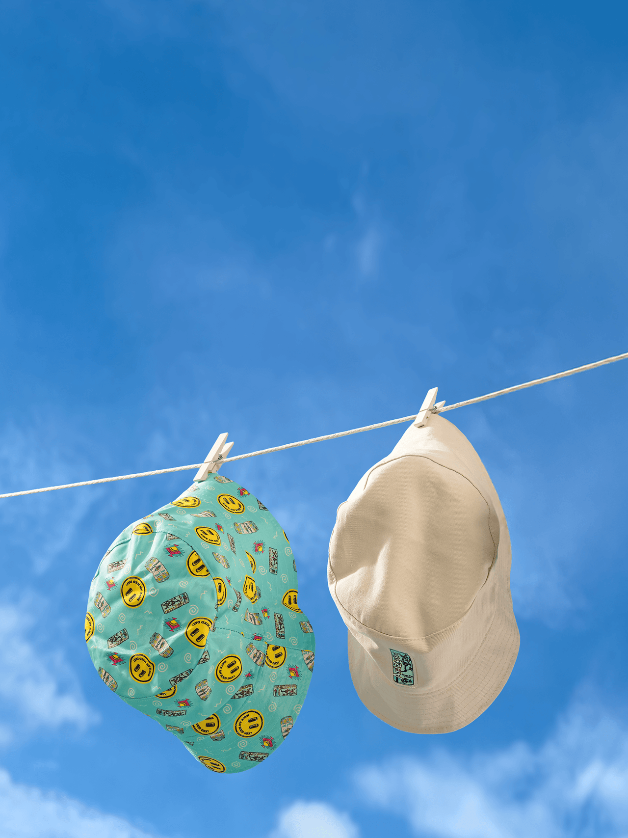 Two az hats hanging on a clothesline against a blue sky.