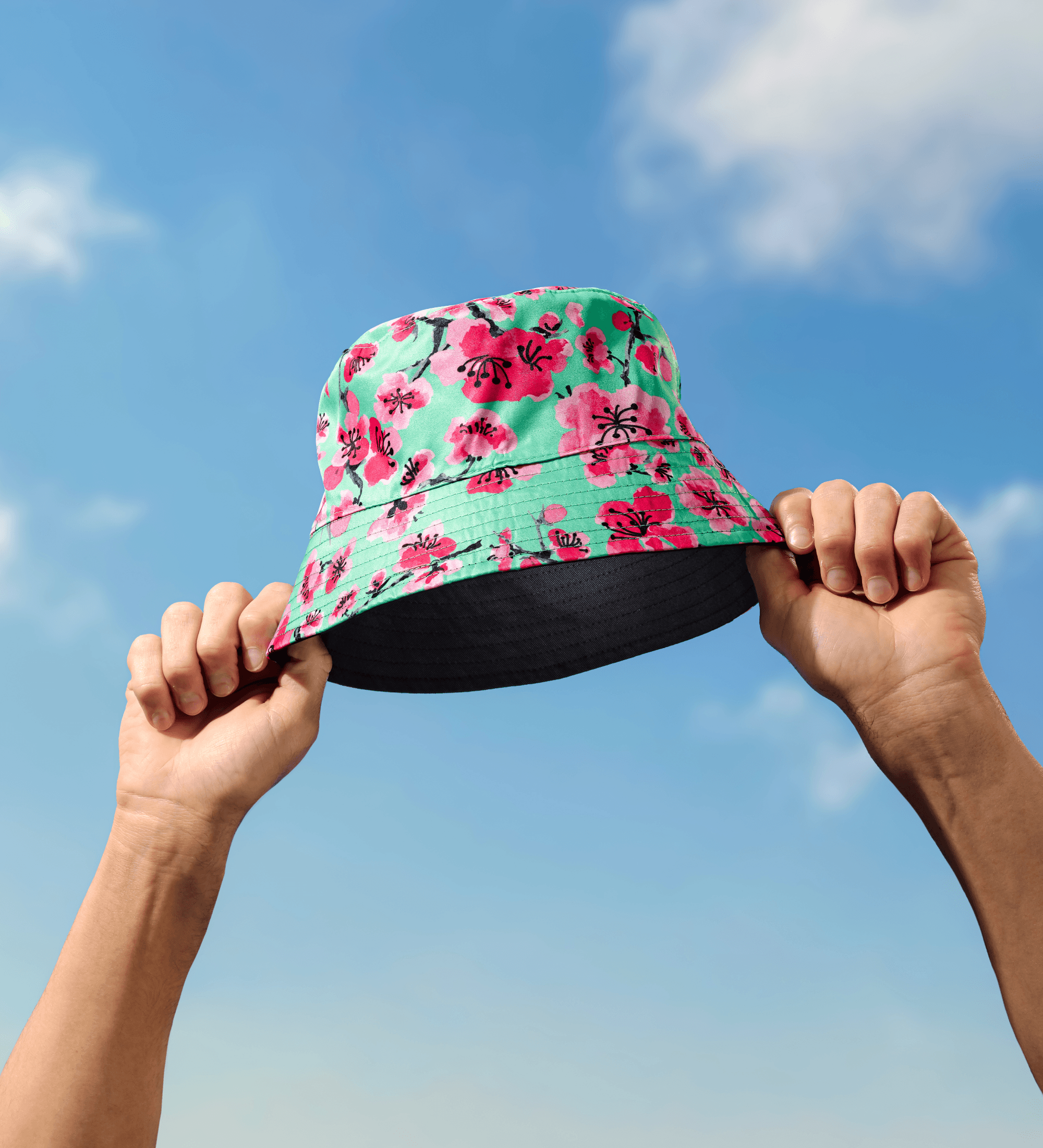 AZ Floral-patterned bucket hat held up against a blue sky