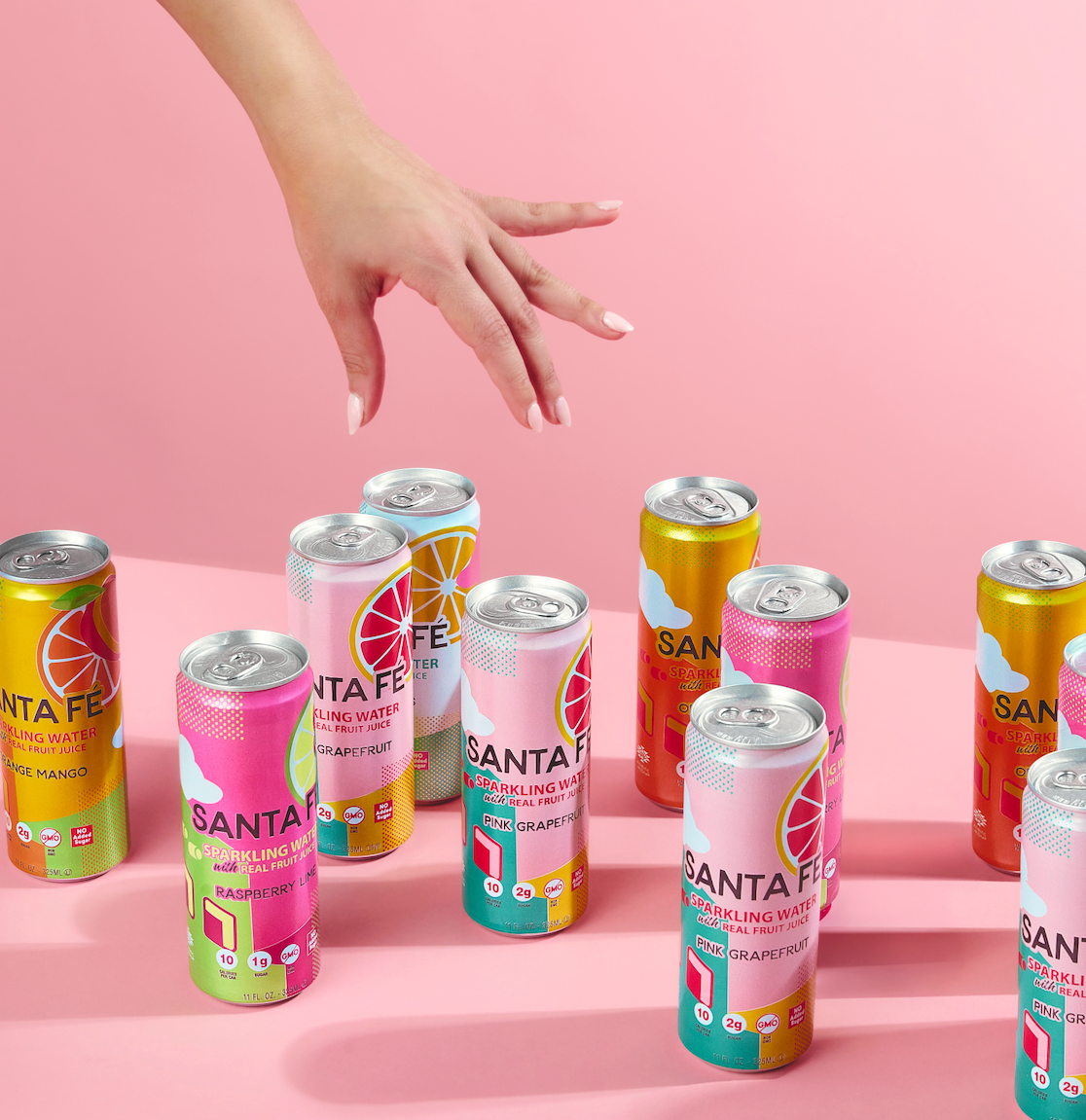Collection of Santa Fe sparkling water cans on a pink background with a hand reaching out.