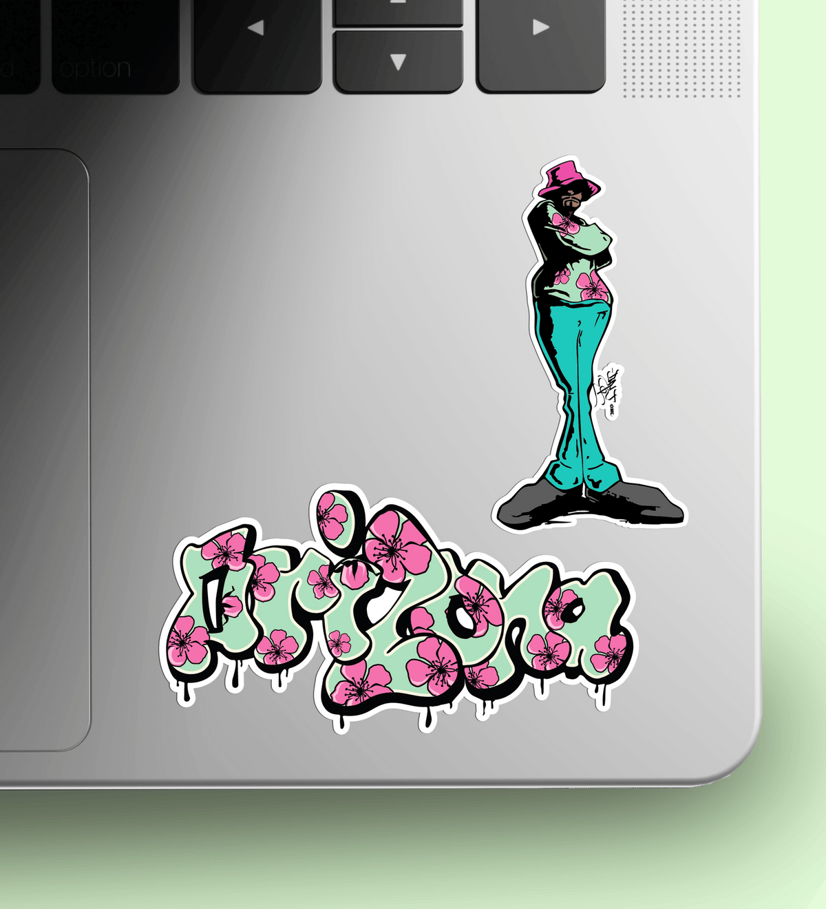 Laptop with a sticker of a person in a hat and green pants, and another sticker with pink flowers and text that reads "Arizona"