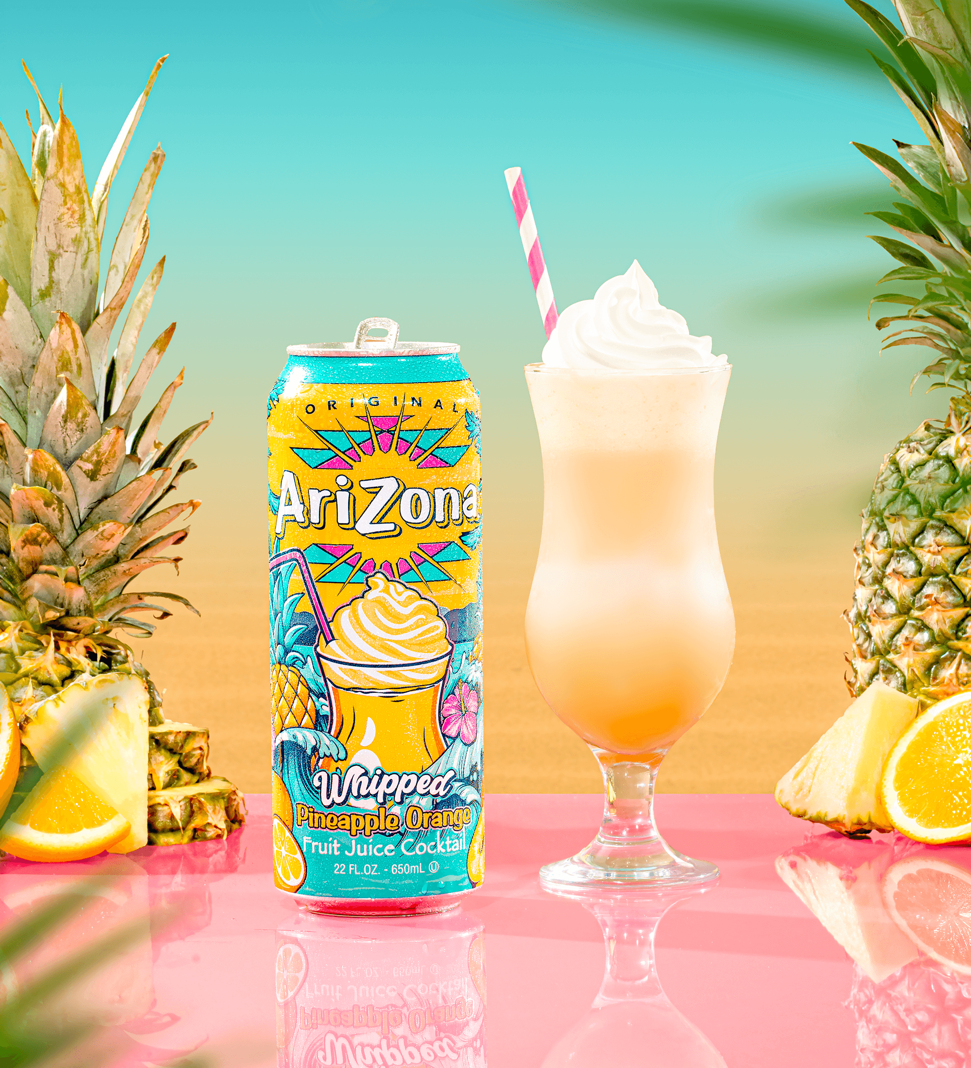 Arizona Whipped Pineapple Orange fruit juice cocktail can with a glass of the drink and pineapples on a colorful background