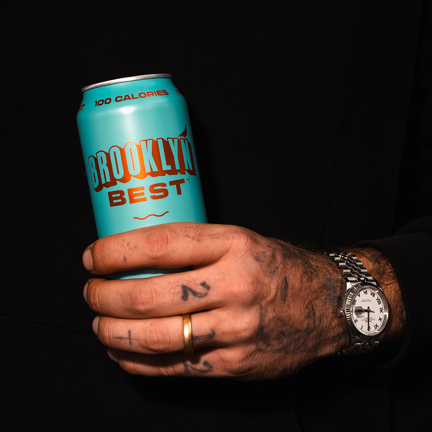 Hand holding a can of 'Brooklyn Best' against a black background
